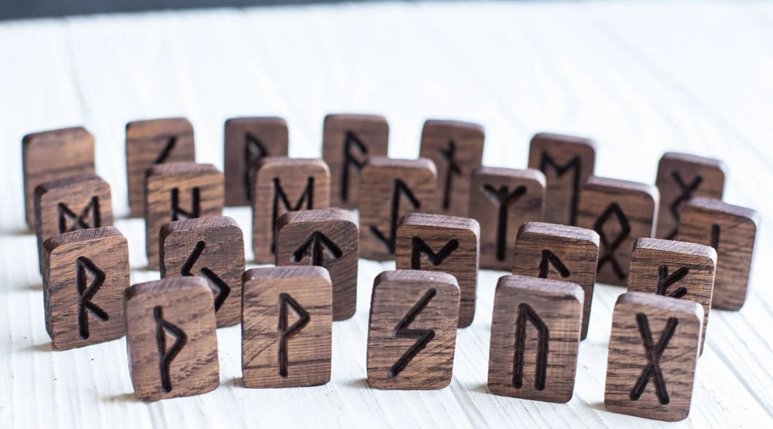 Wooden runes arranged on a textured surface with a candle in the background