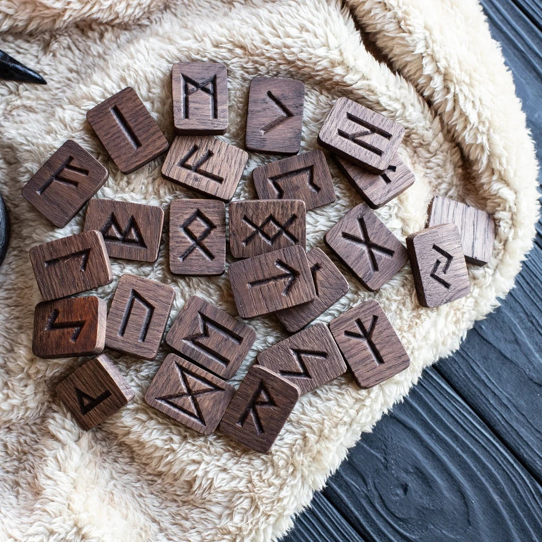 Wooden runes arranged on a textured surface with a candle in the background