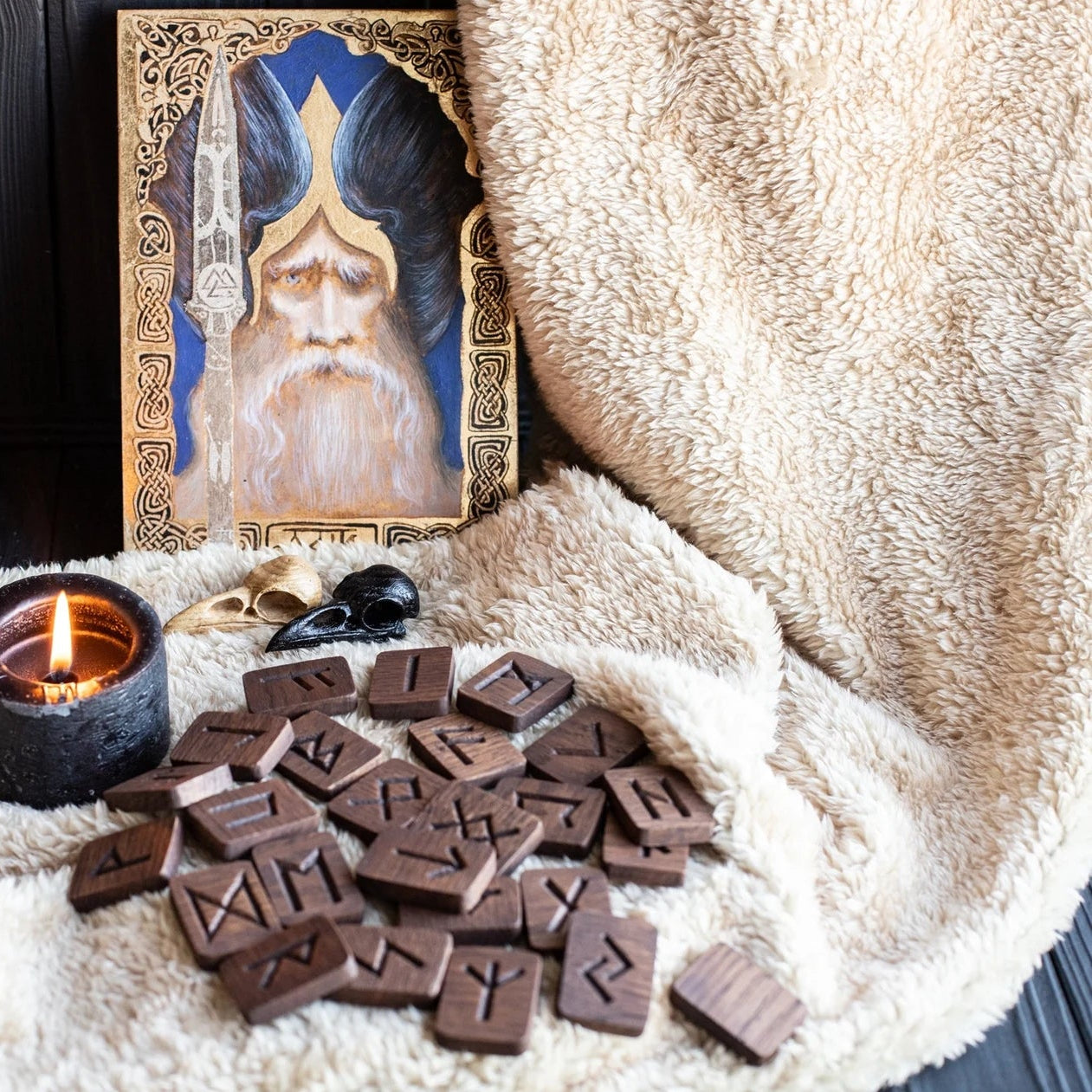 Chocolate runes on a soft surface with a candle and a painting of a bearded figure in the background.